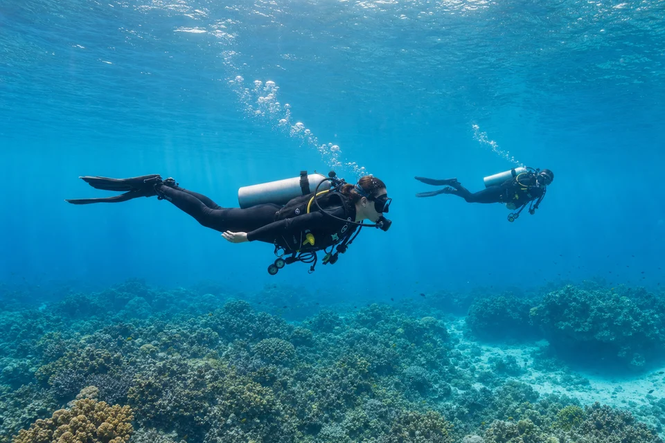 Divers demonstrating excellent horizontal trim above a coral reef